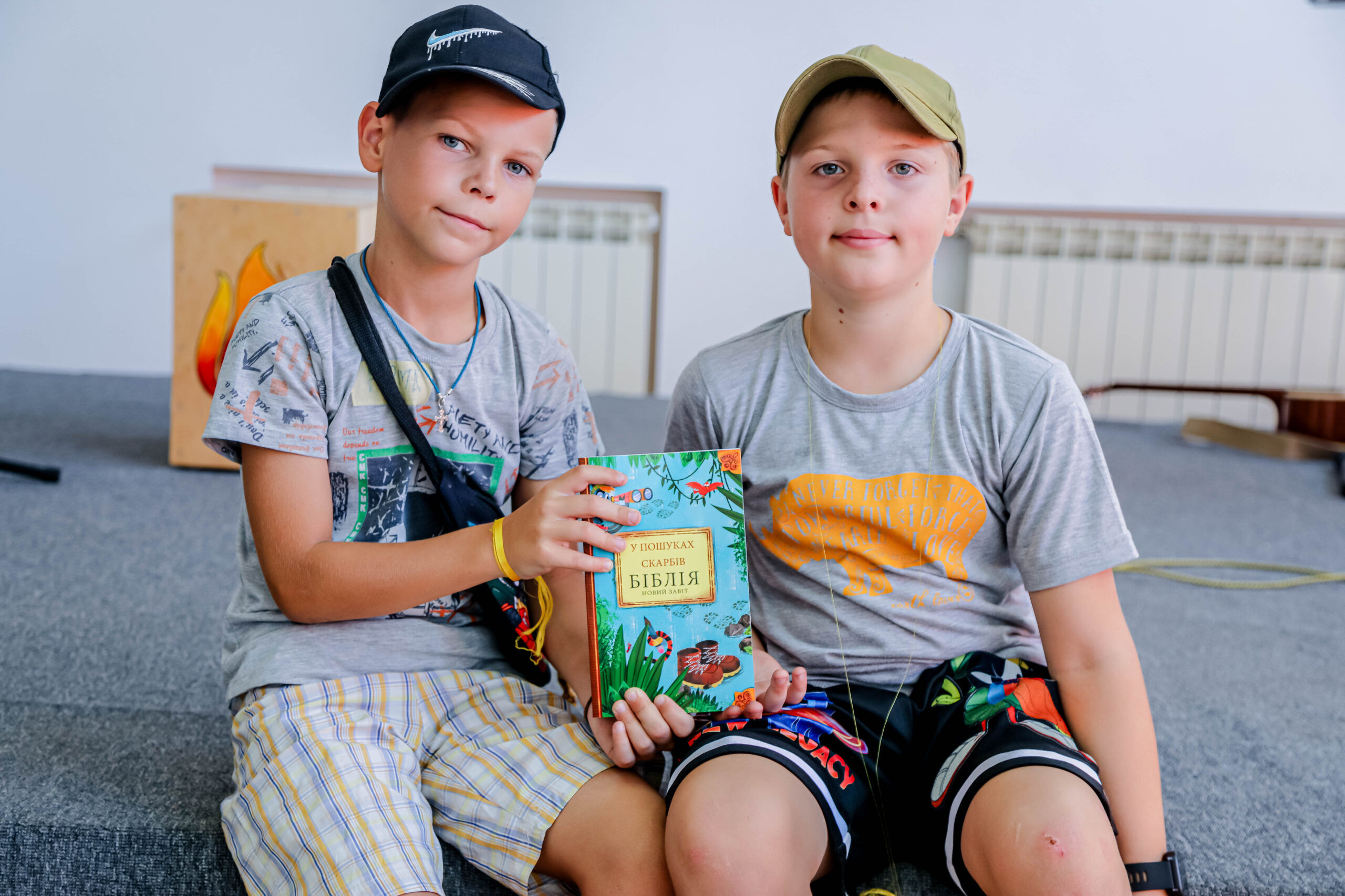 Two boys sitting and holding bible at summer bible camp