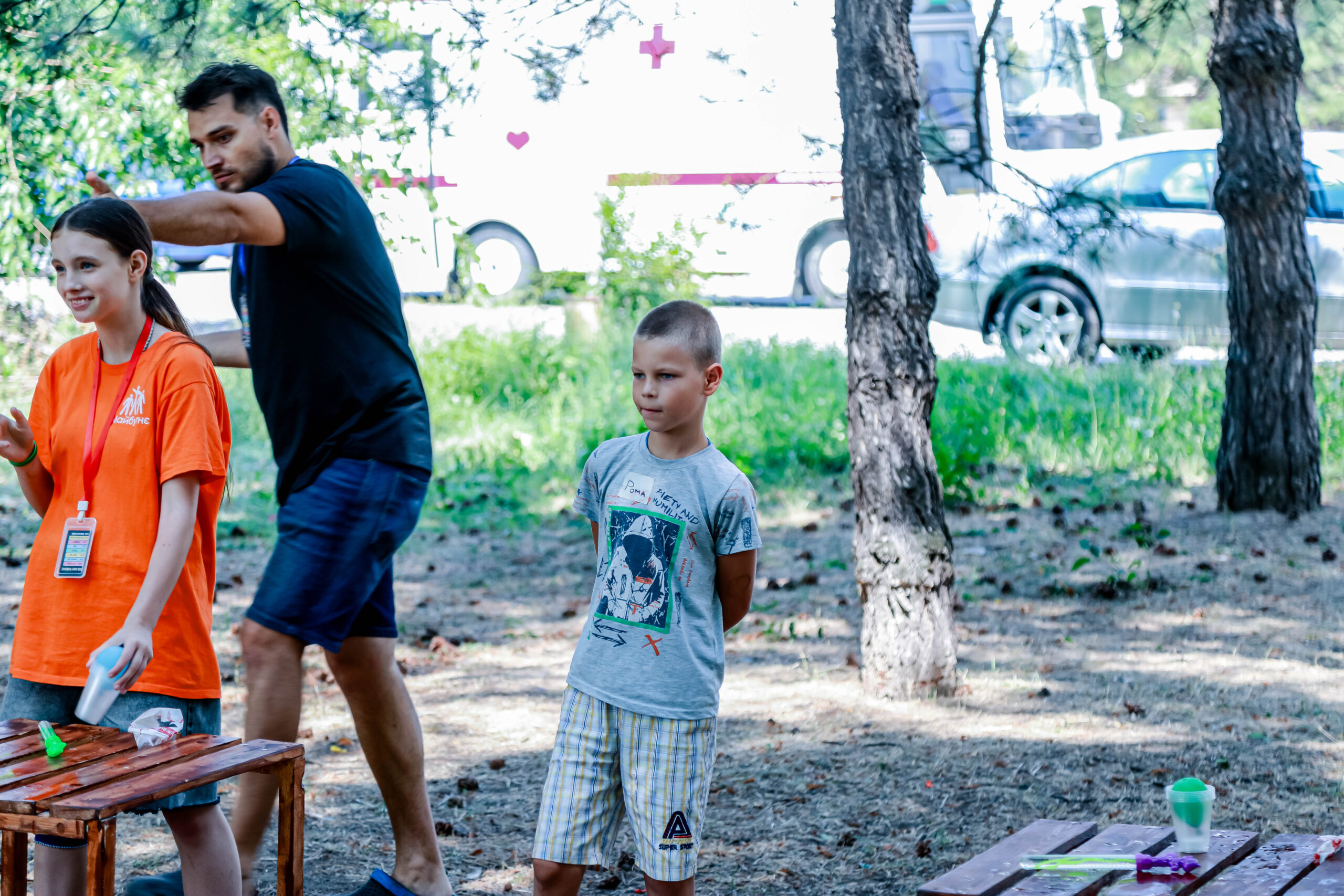Boy playing game out side with two people in the background at summer bible camp