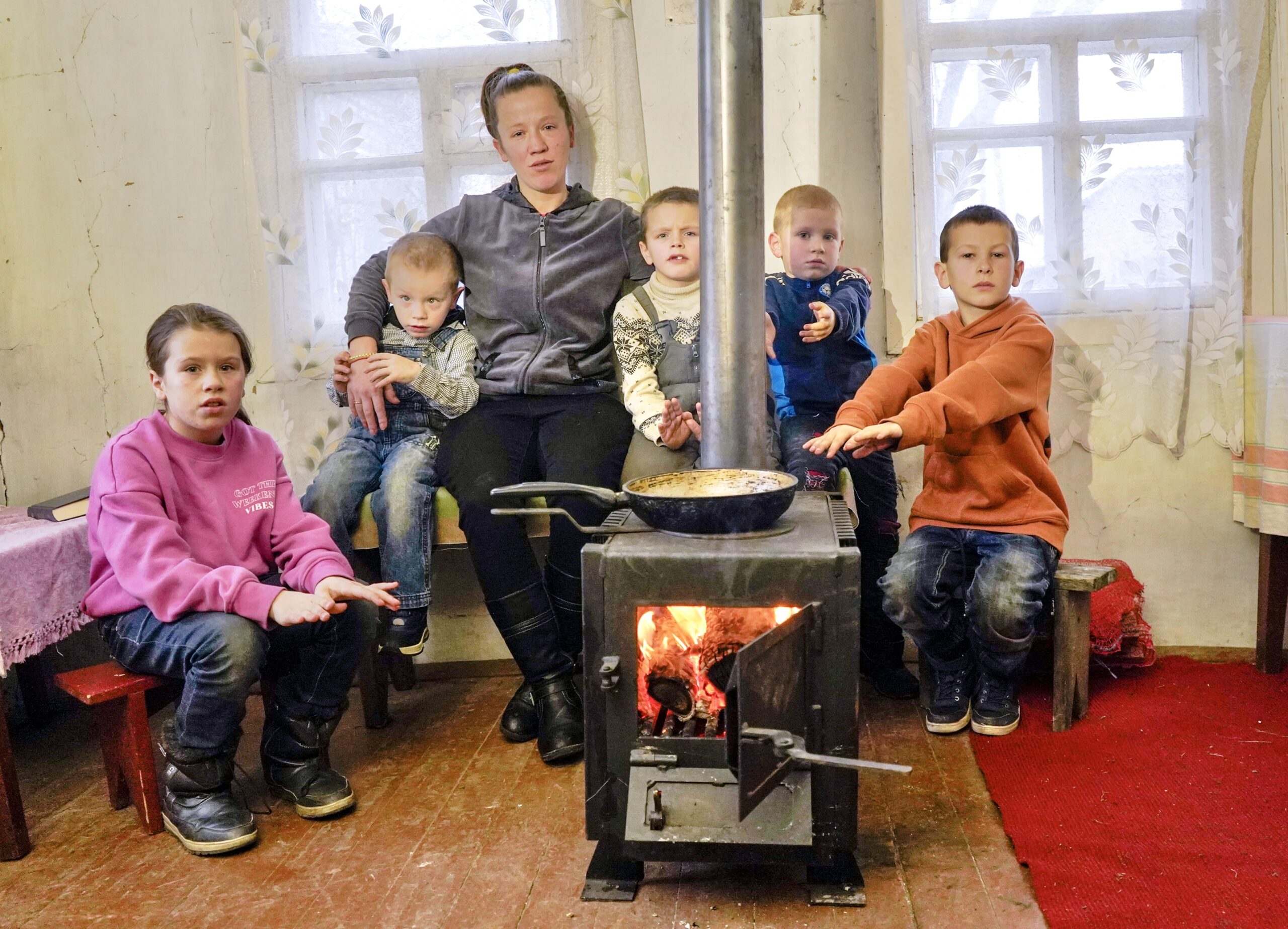 family warming up around wood burning stove