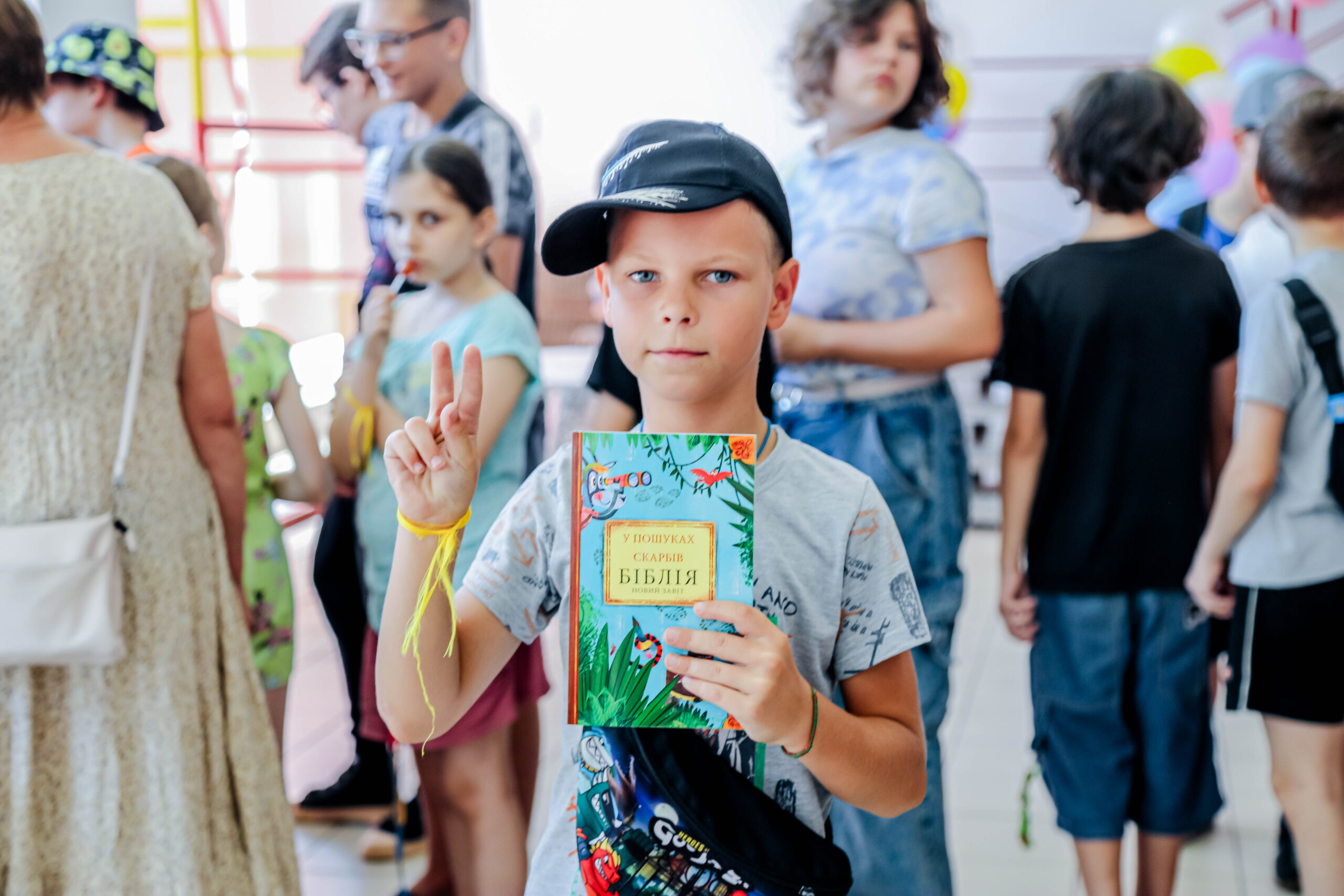 yount boy with hat holding a bible at summer camp