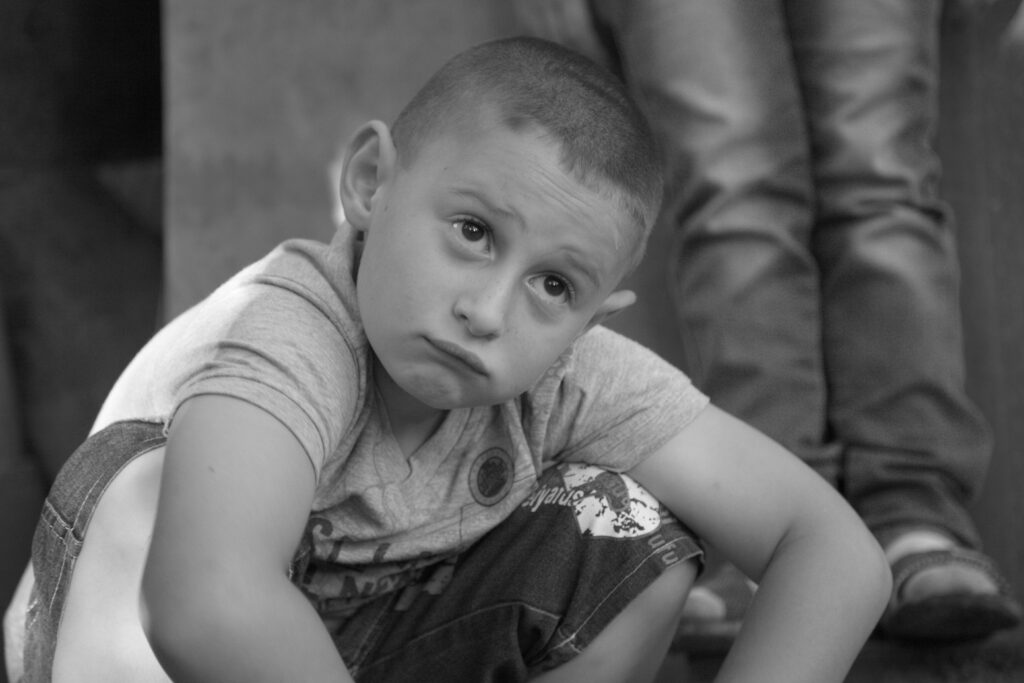 A close-up portrait of a young boy with dark hair and a serious, direct expression.