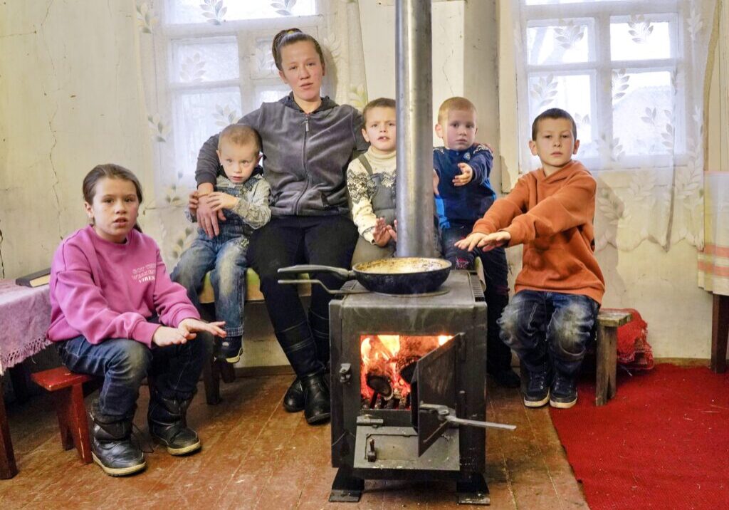 family warming up around wood burning stove